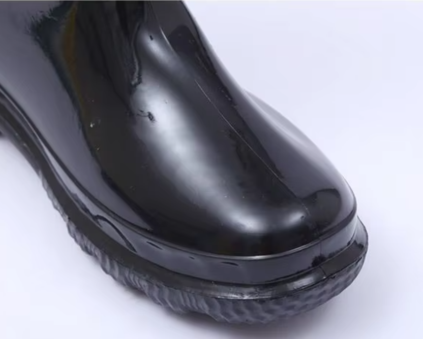 a092bfdc-7822-4703-8756-0930a4d9c5b3_ภาพถ่ายระยะใกล้ของหัวรองเท้าทรงมนบนรองเท้าบูททำงานกันน้ำทำจากพีวีซีสีดำมันวาวและให้ความอบอุ่น.png